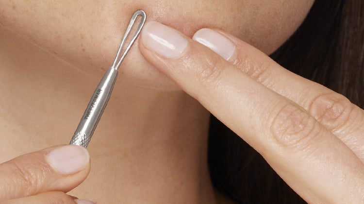 Close-up of a person using a silver tool on their skin